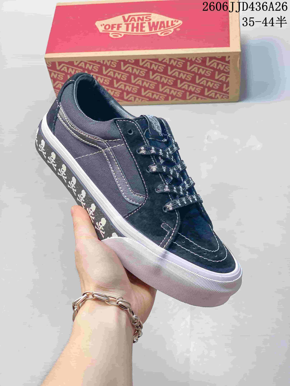 Angled side view showing the black Vans SK8-Low sneaker, white side stripe, skull graphics, and white rubber sole.