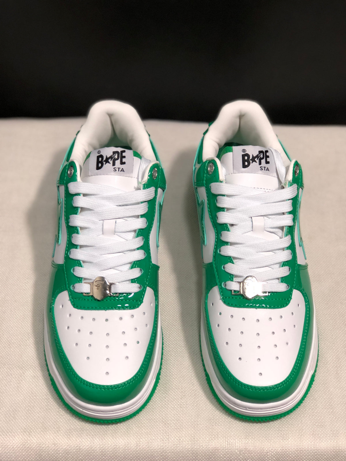 Front view of the pair showing white perforated toe boxes, green trim, white laces, and tongue branding.
