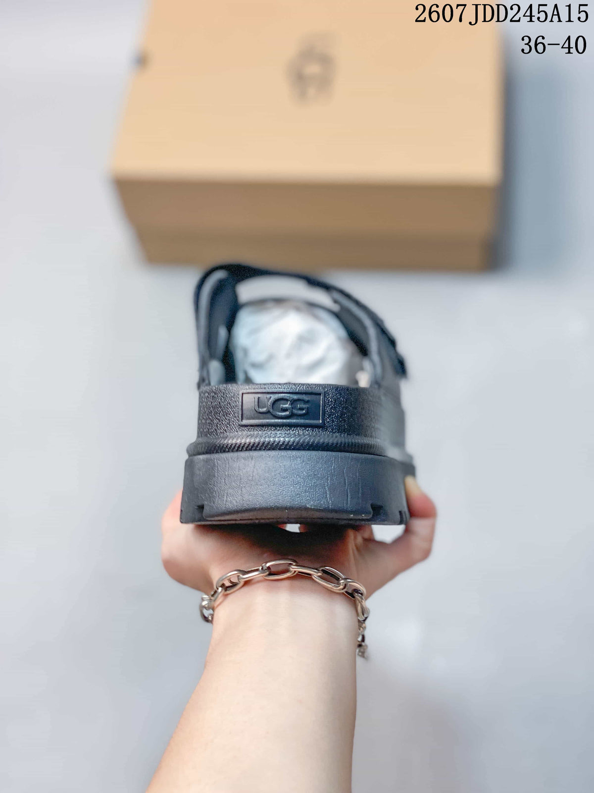 Rear view of a black sandal showing the UGG heel branding and raised sole.