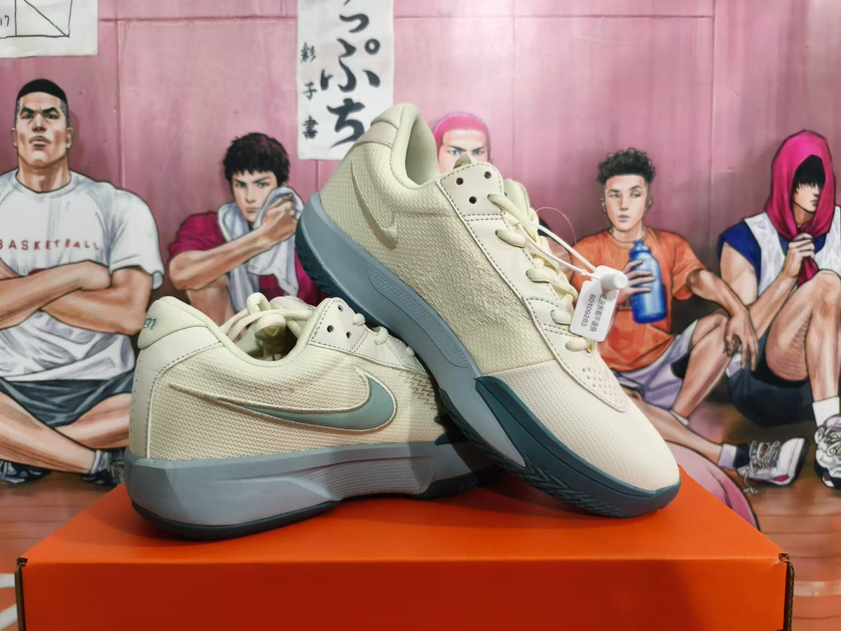 Angled view of a pair of light beige Nike shoes with gray and teal accents.