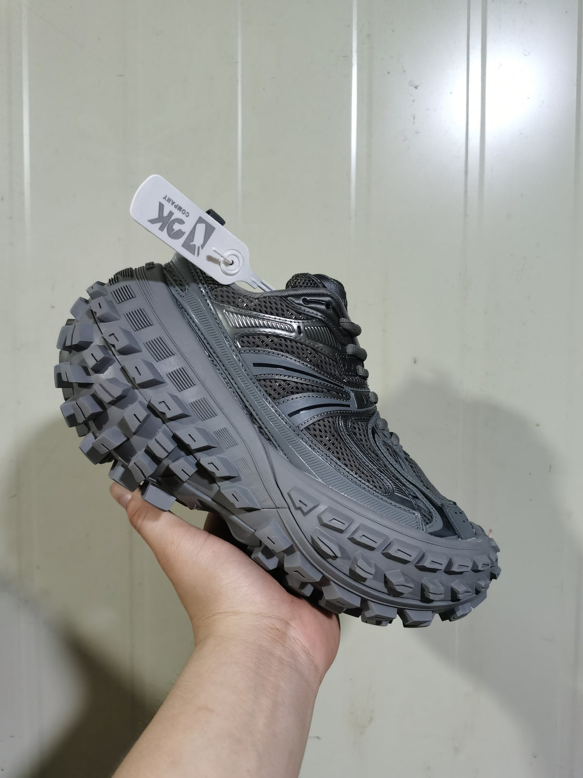 Angled view of the dark gray sneaker highlighting its lace-up design, perforated side panels, and deep outsole tread.
