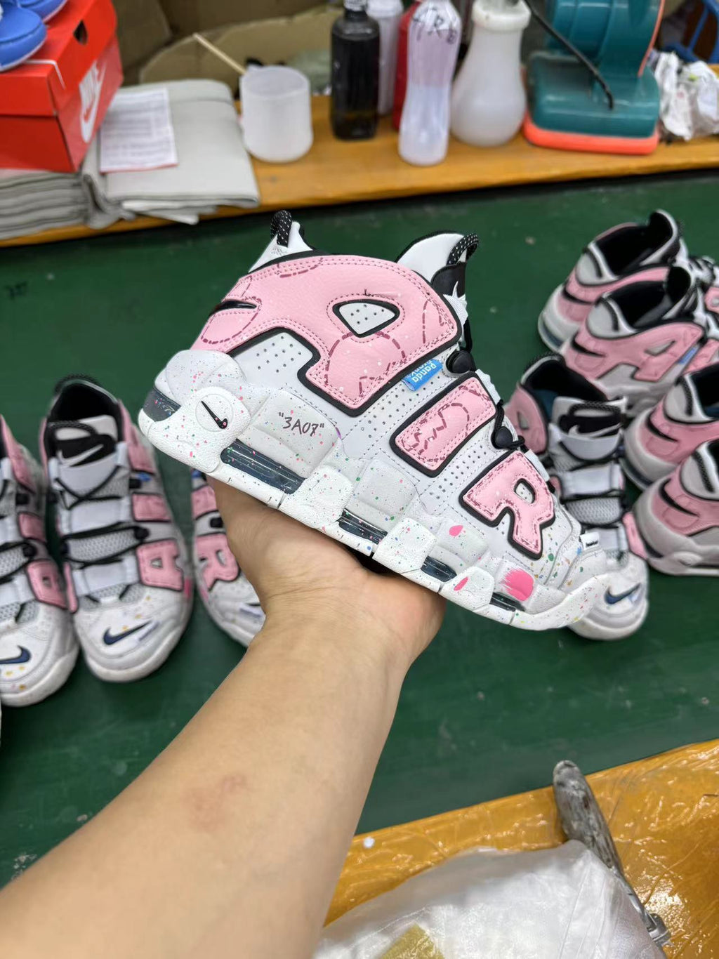 Pink and grey Nike sneaker held in hand, with other pairs visible in the background