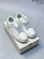 Pair of mostly white low-top sneakers with grey accents and patterned laces displayed on a shoebox.