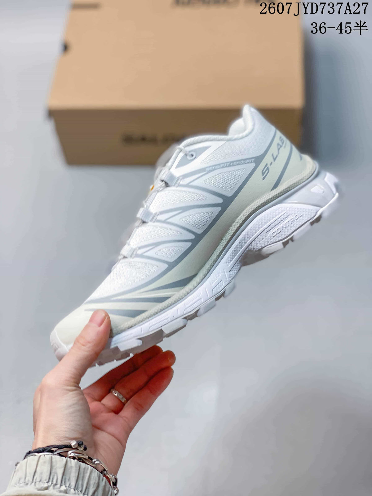 Side profile of the white and gray low-top sneaker showing layered overlays, cord-style lacing, and the lugged sole.