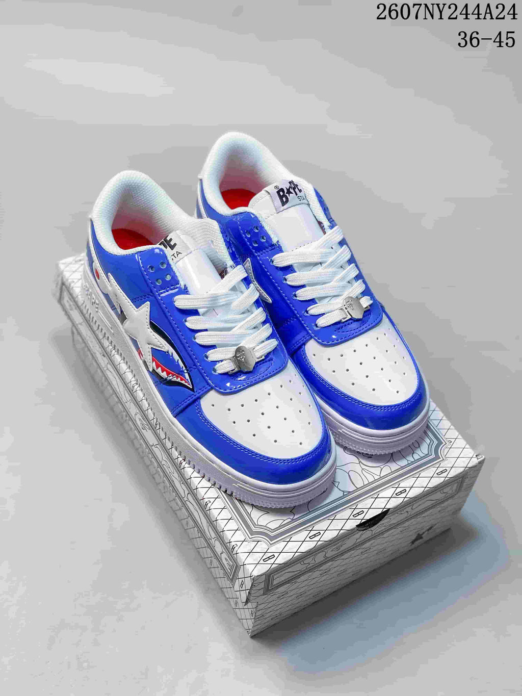 Pair of blue and white low-top sneakers displayed on a patterned box, showing star and shark side graphics.