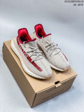 Pair of light knit Adidas Yeezy Boost 350 V2 sneakers with red accents displayed on a shoebox.