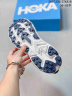 Underside view of a blue and white HOKA shoe showing the patterned outsole tread.