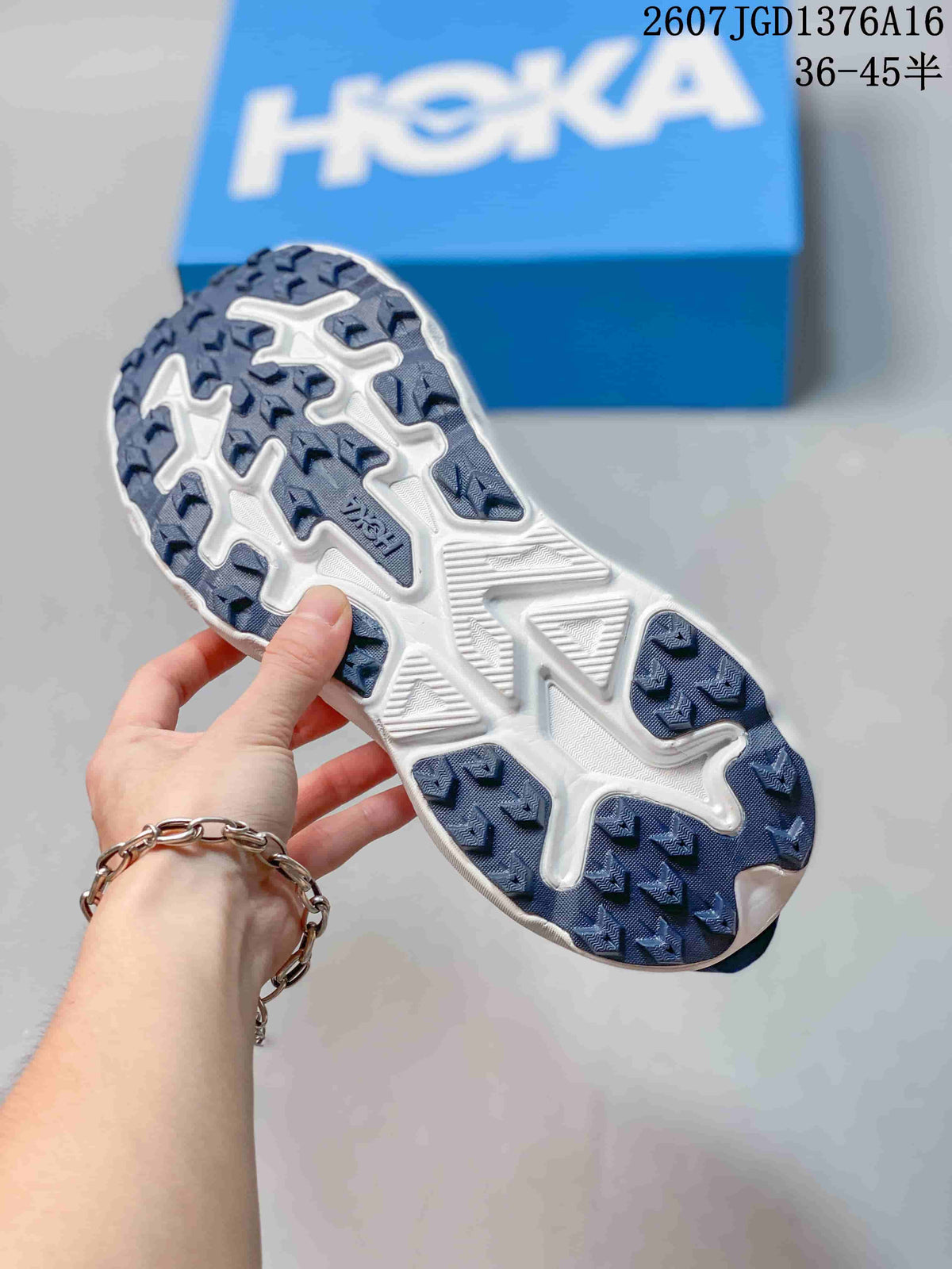 Underside view of a blue and white HOKA shoe showing the patterned outsole tread.