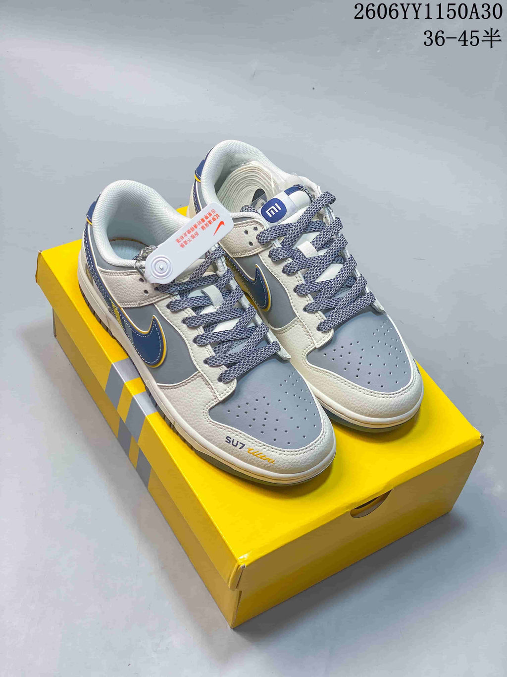 Pair of white and gray sneakers with navy and yellow details and patterned laces