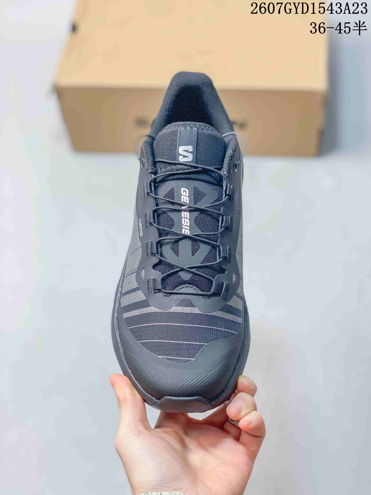 Front view of the Salomon Genesis shoe showing the dark gray upper, lace system, tongue branding, and reinforced toe area.