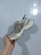 Top and side view of the beige and grey sneaker showing the laces, mesh panels, layered upper and outsole.
