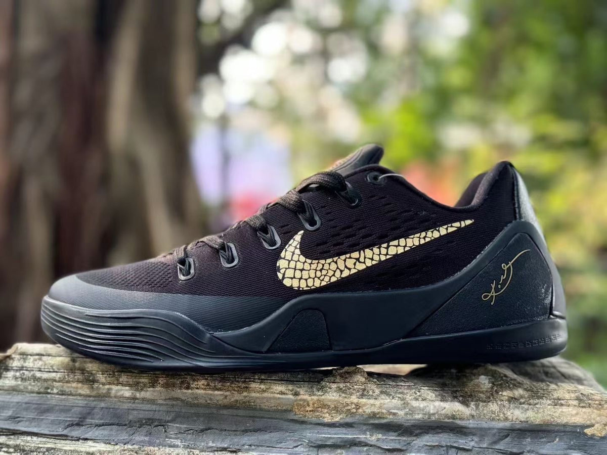 Opposite side view of a black Nike Kobe 9 shoe showing gold-toned branding and signature detail.