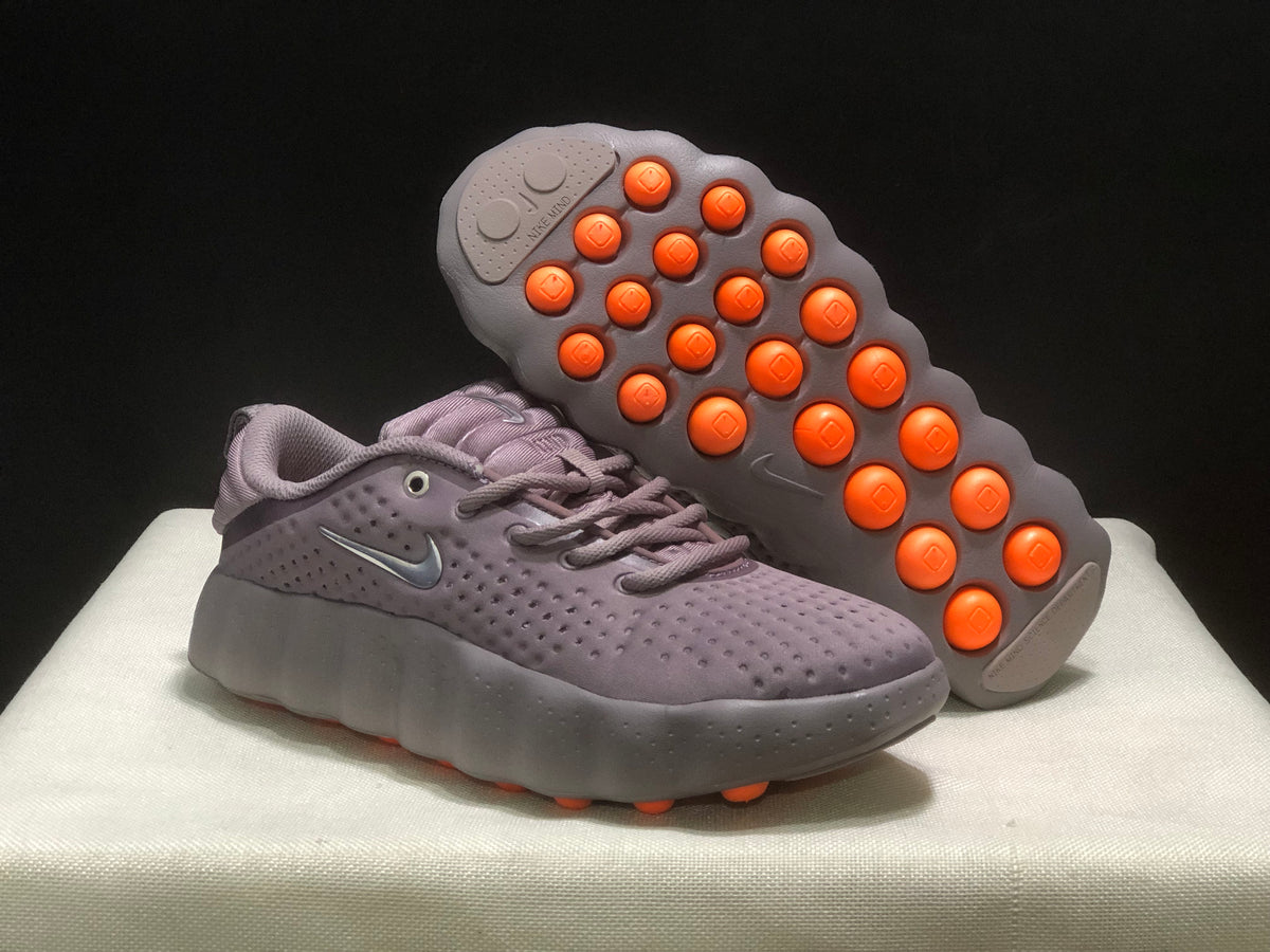 Angled view showing the orange circular outsole elements beneath one sneaker.