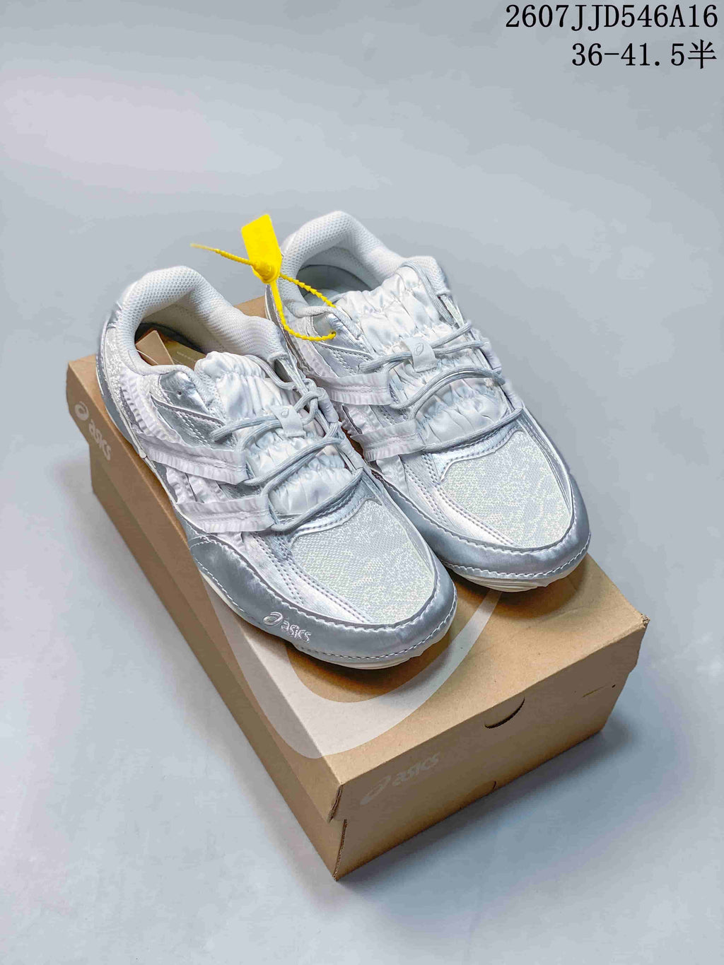 Pair of silver and white ASICS Hypersync sneakers displayed on a shoebox; overlay text shows style reference 2607JJD546A16 and sizes 36–41.5.