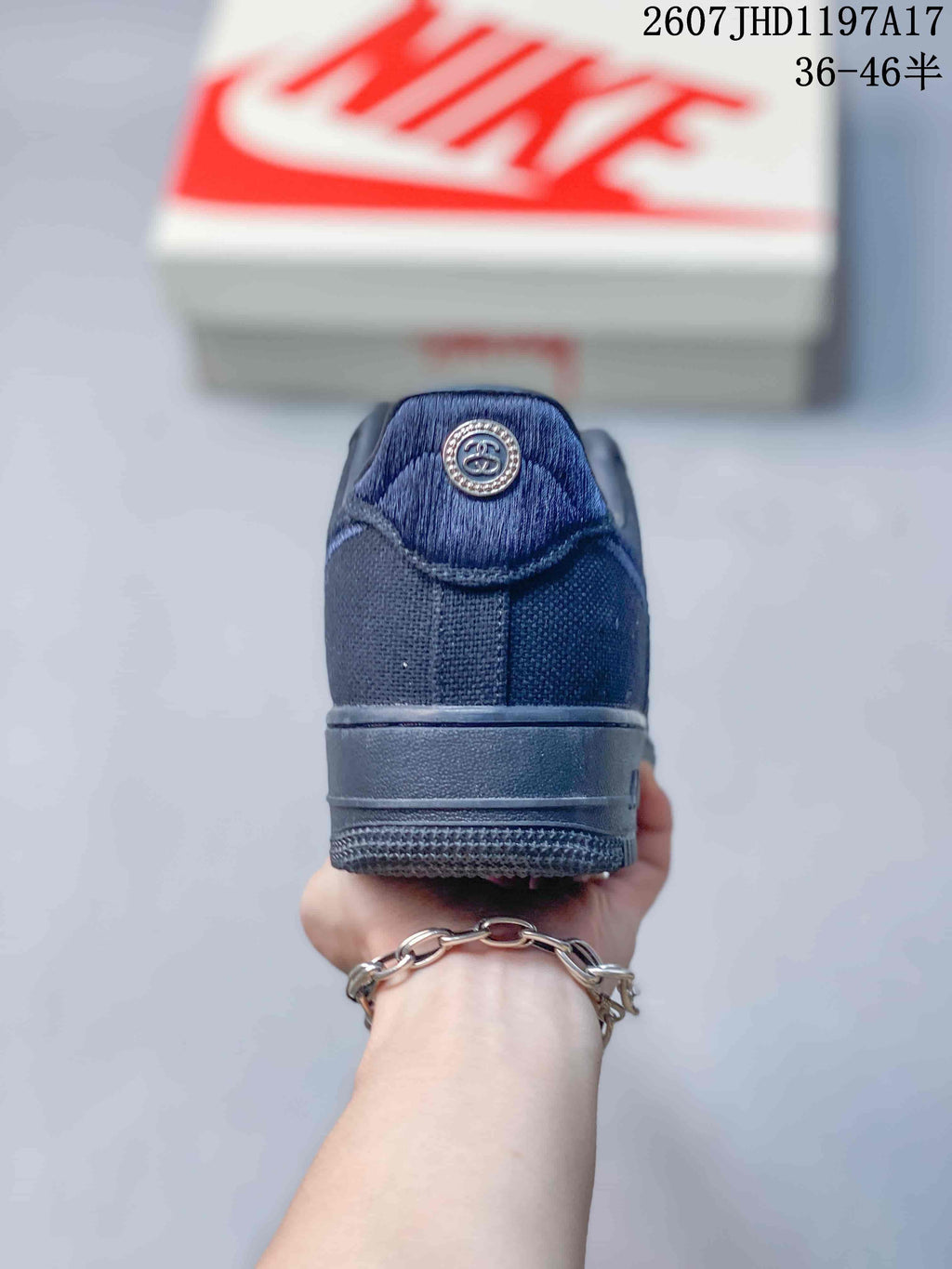 Rear view of the black sneaker showing the padded heel, tonal stitching and circular Stussy-style heel emblem.