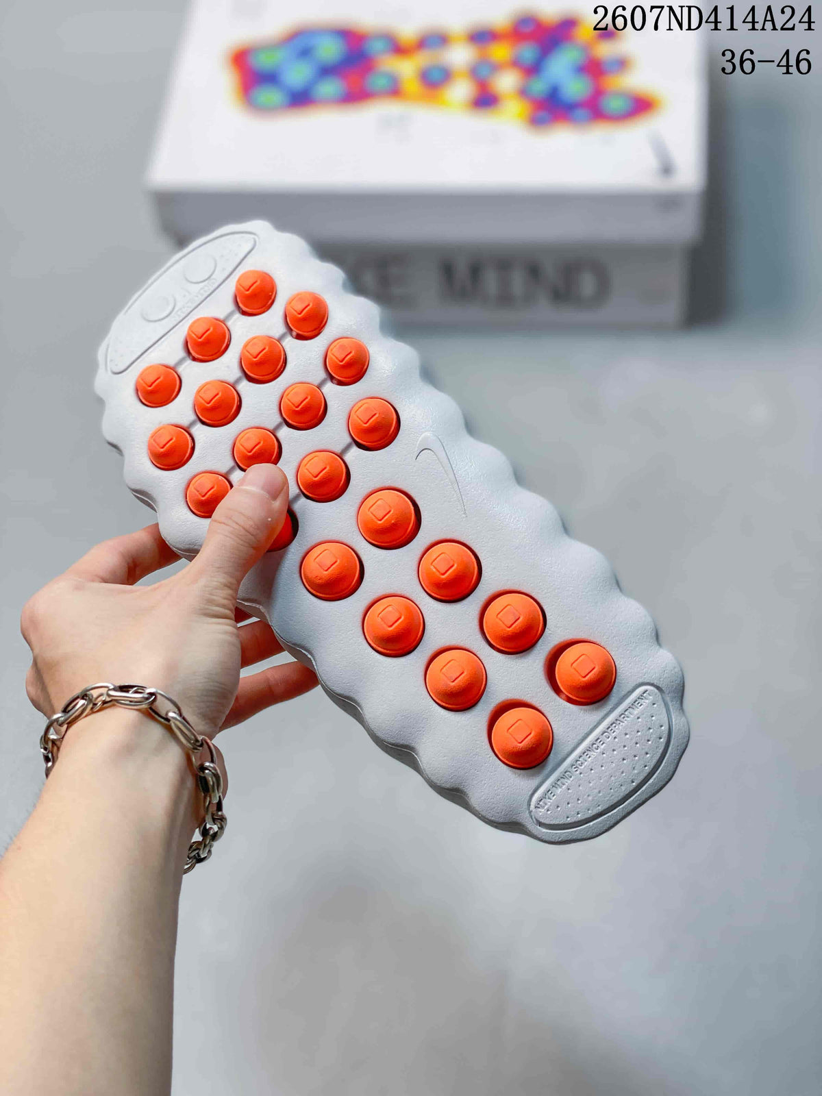 Underside view showing the textured light gray outsole and multiple orange cushioning elements.