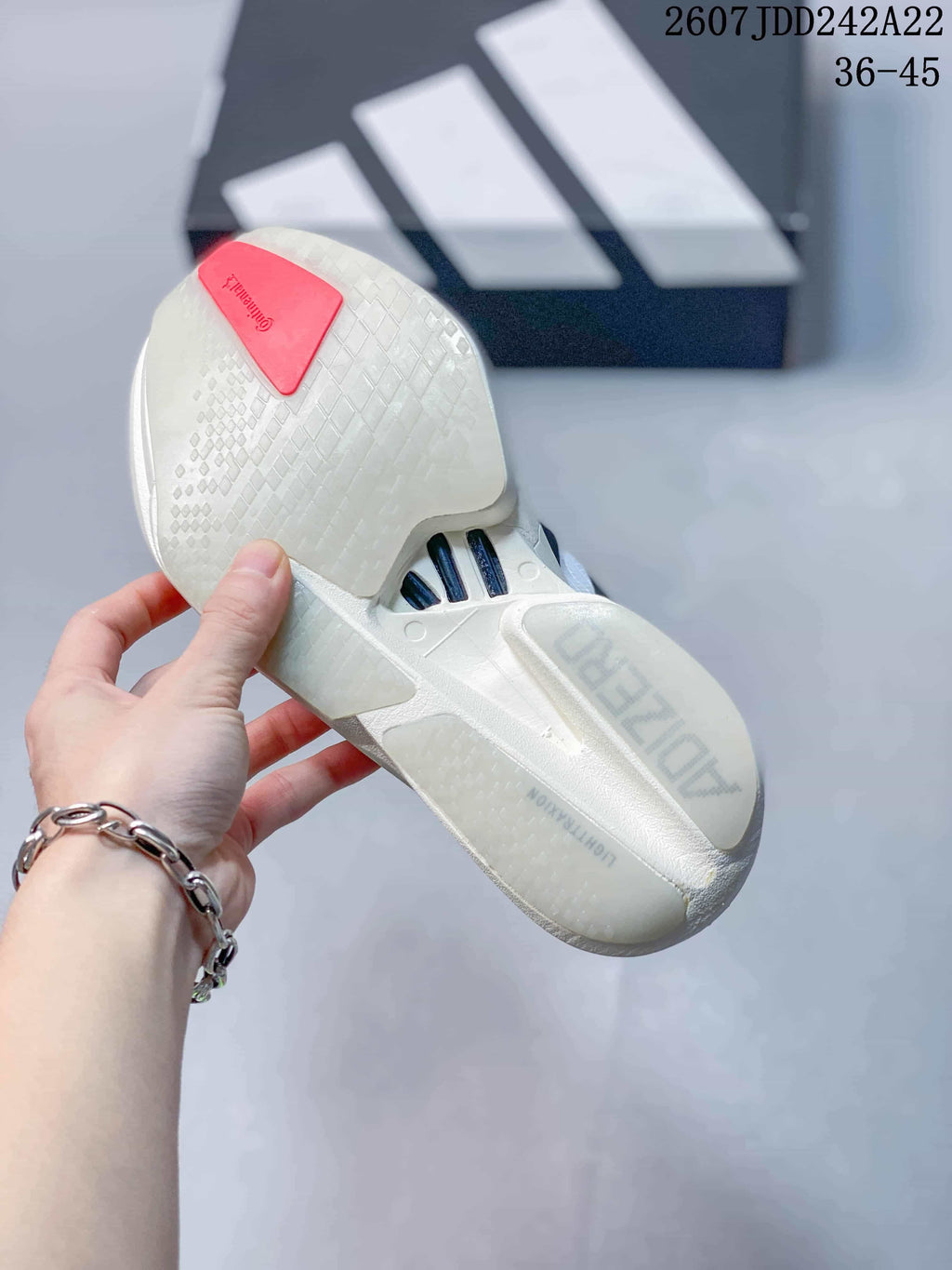 Underside view showing the white patterned outsole, red heel insert, and black-and-white shoe box.