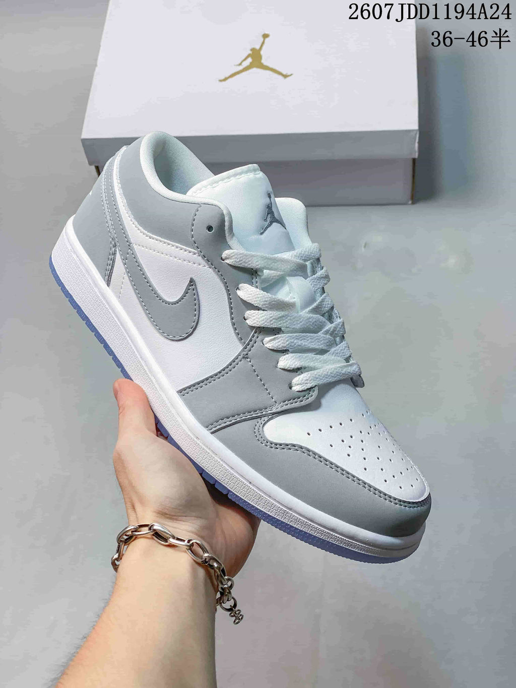 Grey and white low-top Jordan sneaker shown from a front three-quarter angle, with grey overlays, white laces, and a translucent-looking outsole edge.