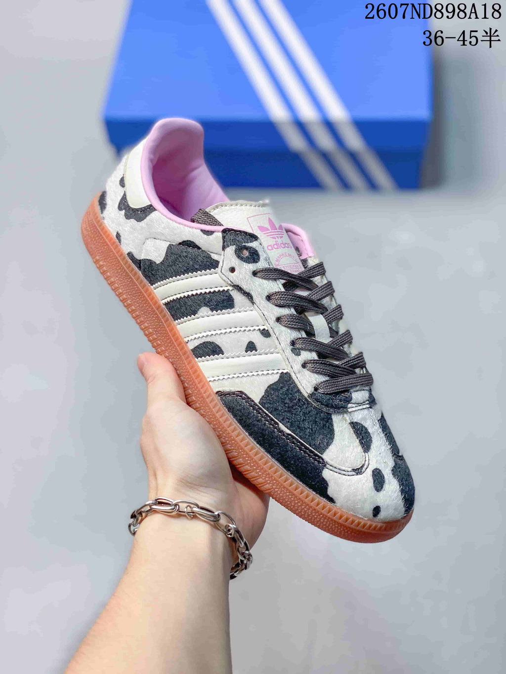 Angled side view of the adidas Samba OG sneaker with cow-print panels, white stripes and gum outsole.