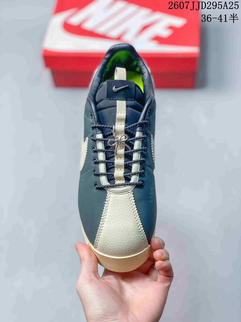 Top view of the sneaker showing the cream toe panel, navy upper, center lace detail, and tongue branding.
