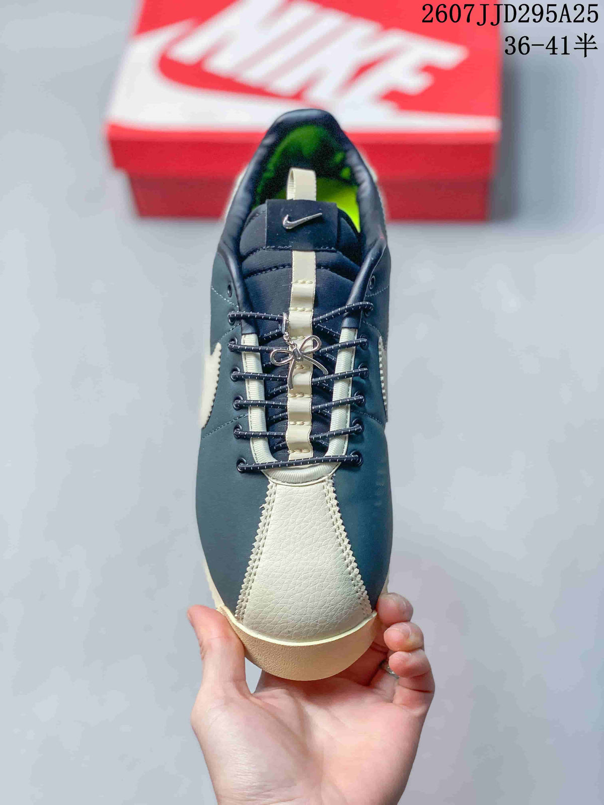 Top view of the sneaker showing the cream toe panel, navy upper, center lace detail, and tongue branding.
