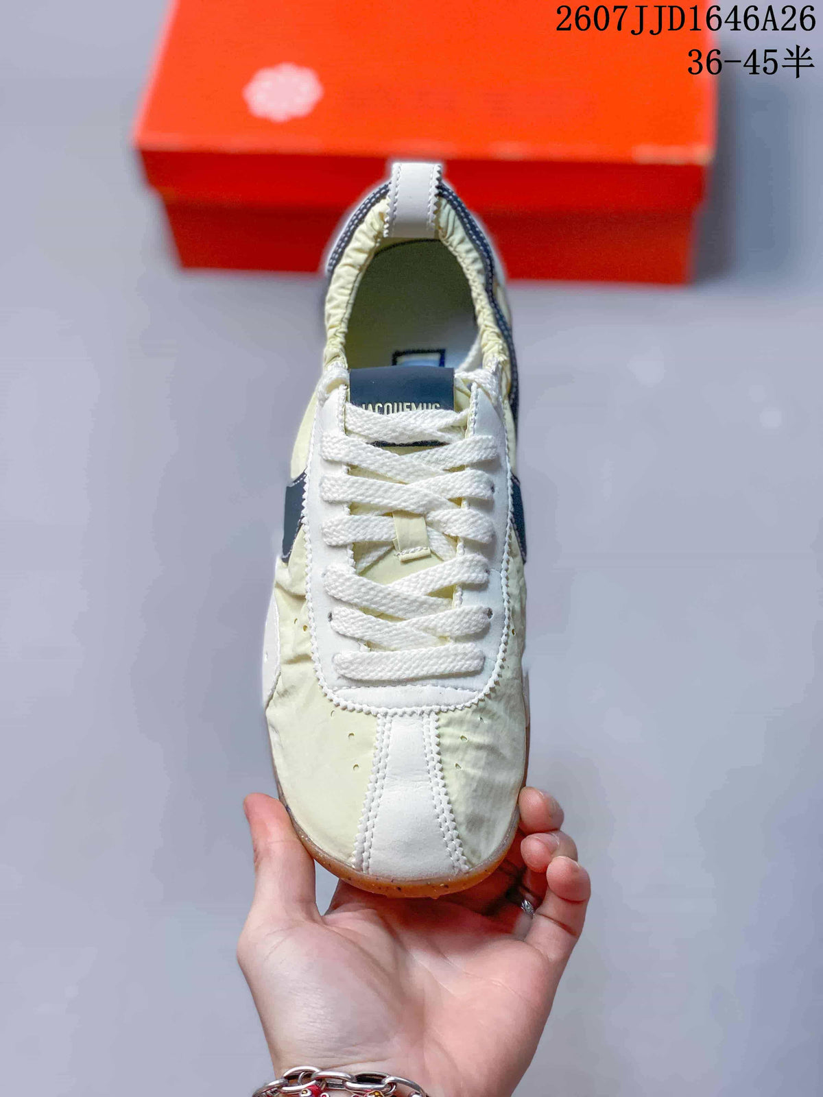 Top view showing white laces, cream panels, white stitched details, and the navy tongue label.