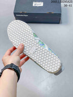 Underside of the sneaker showing a textured white rubber outsole and an Onitsuka Tiger box in the background.