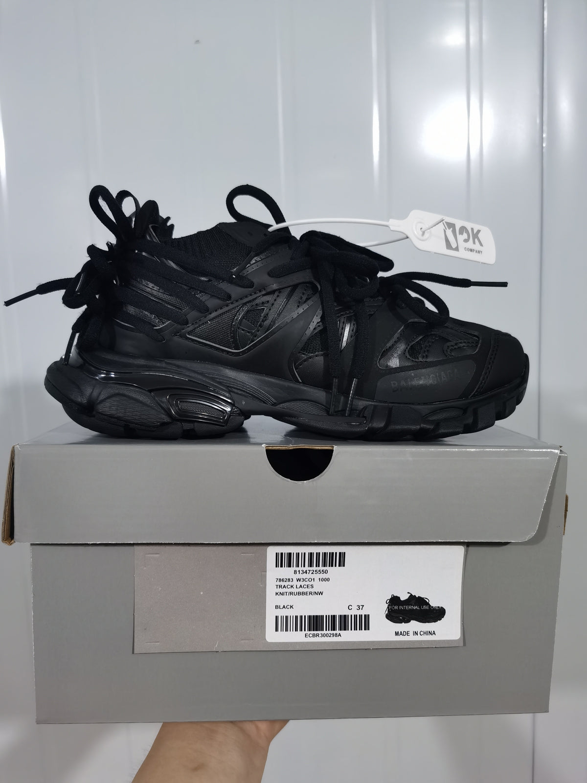 Side profile of the black sneaker resting on a gray shoe box with a visible product label.