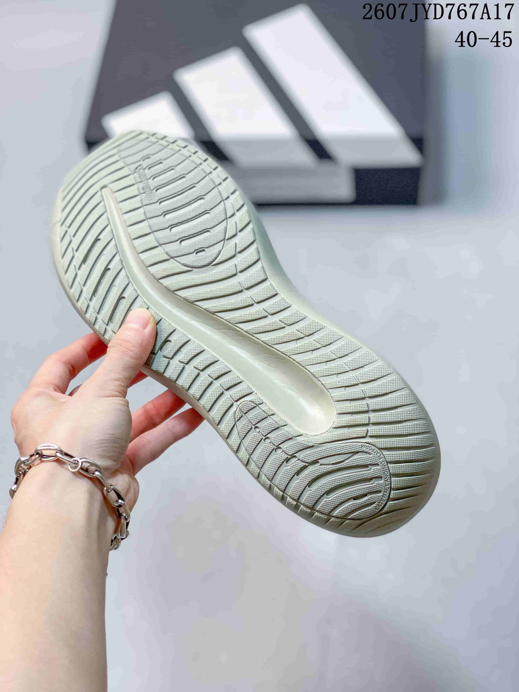 Close view of the sneaker outsole showing a light-colored rubber sole with repeated curved traction grooves.