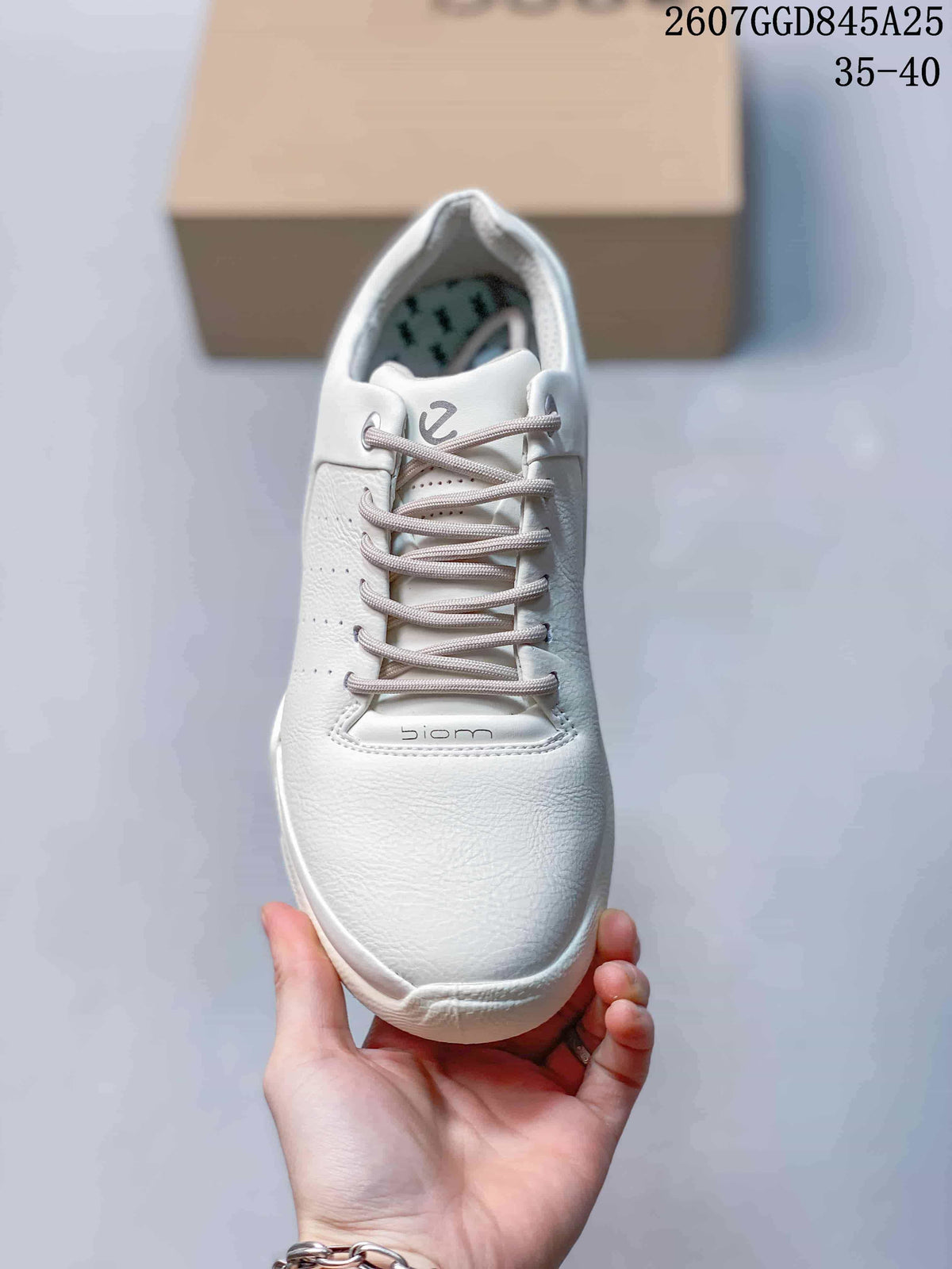 Front view of a white lace-up sneaker with perforated side panels and Biom branding on the tongue.