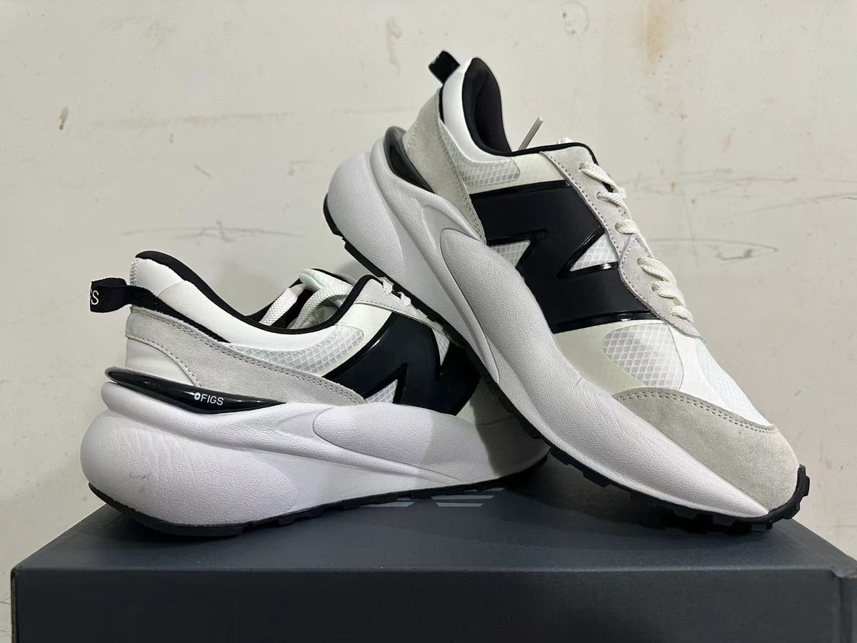 Pair of white and light gray sneakers shown from the side, with black accents and chunky soles