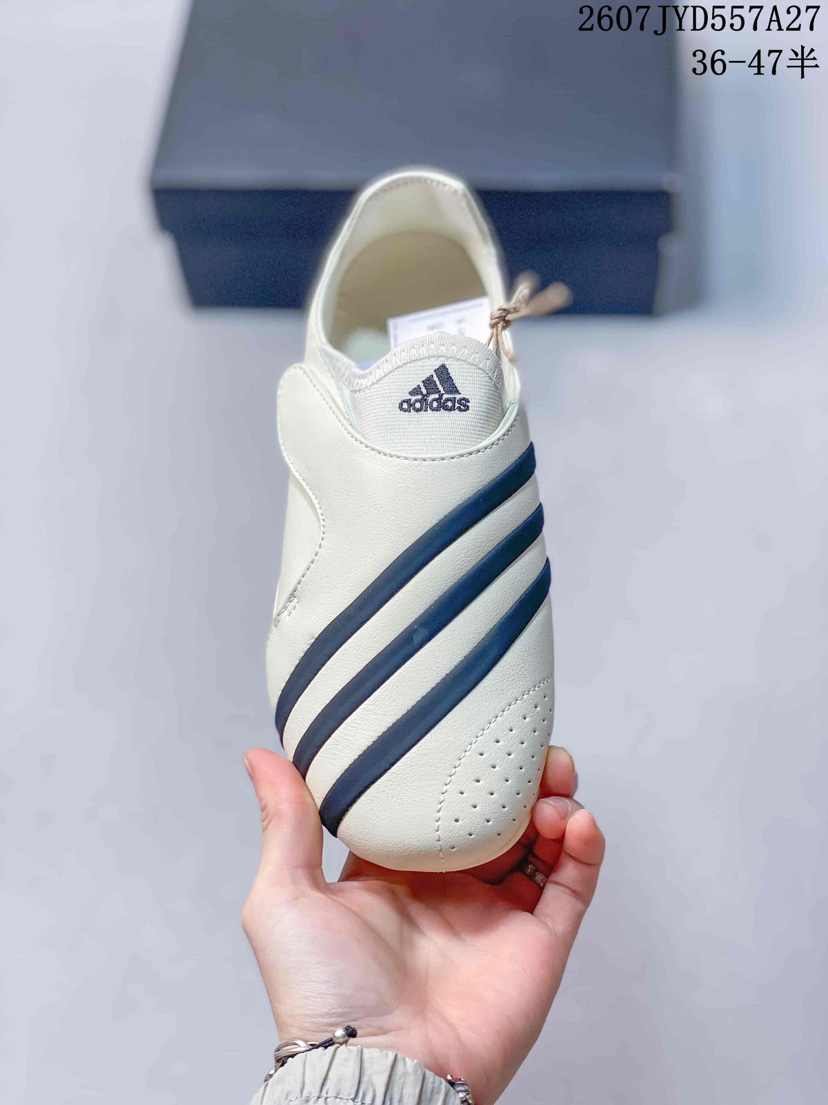 Top view of the sneaker showing the off-white upper, navy diagonal stripes, and adidas tongue branding.