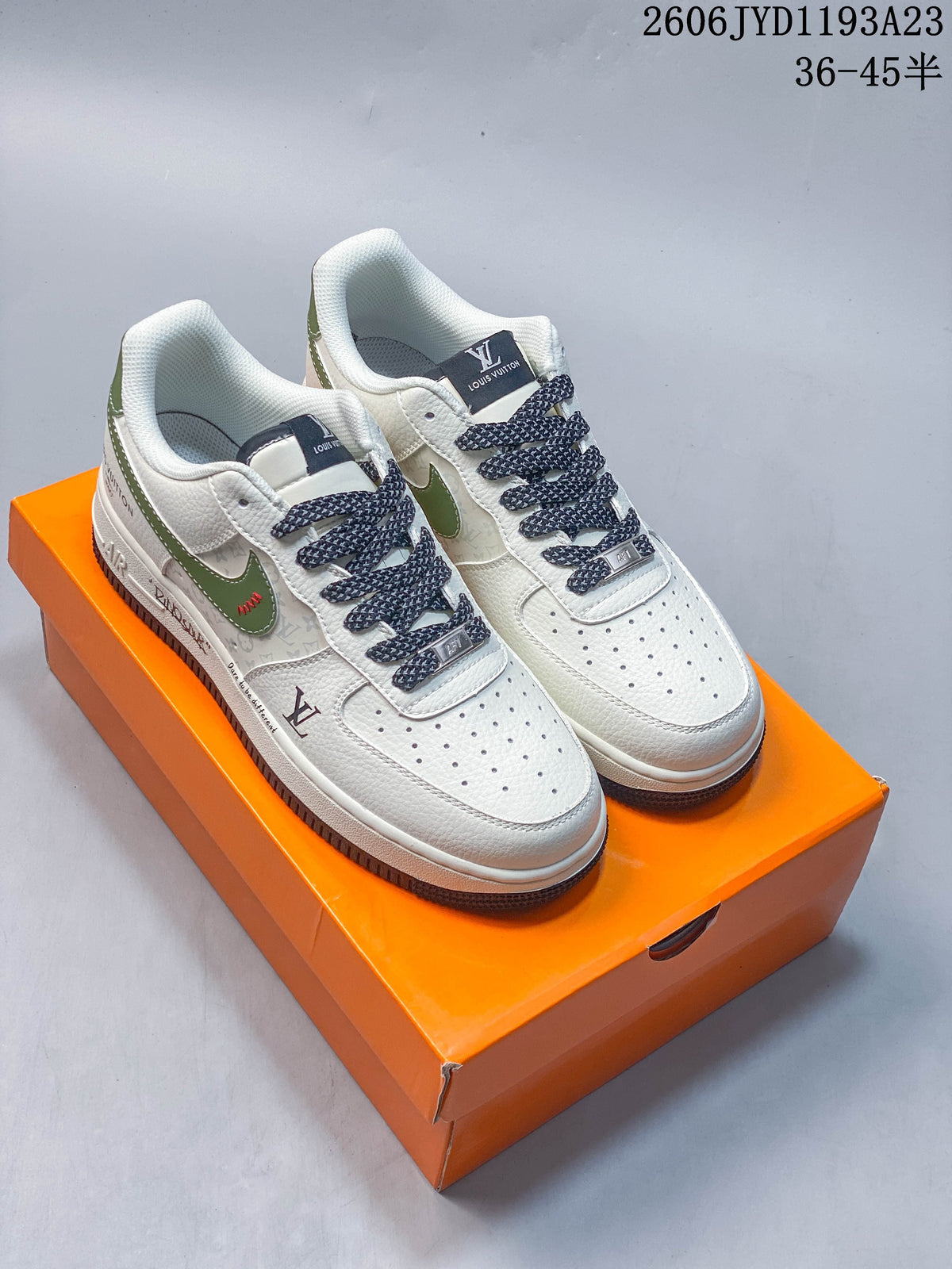 Pair of white and green low-top sneakers with dark patterned laces on an orange box.