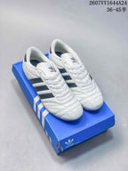 Pair of white adidas Taekwondo sneakers with dark navy stripes on a blue adidas shoebox; overlay shows style code 2607VY1644A24 and size range 36–45.