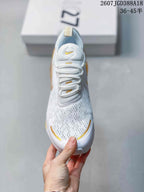 Top view of the white sneaker with gold accents, laces, and patterned upper.