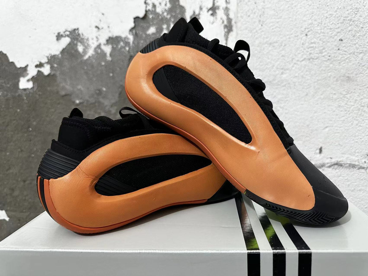 Black and orange basketball shoes arranged to show their sculpted side panels and outsole.
