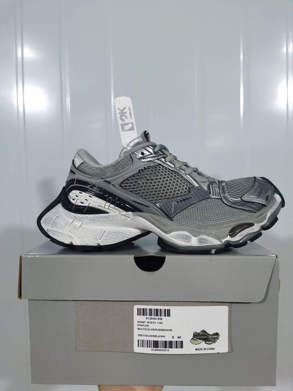 Pair of gray, silver and black sneakers displayed on a shoebox; the box label shows size E 40 and the color text “GREY/SILVER/BLK/W”.