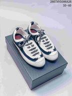 Black and white low-top sneakers displayed on a dark shoe box, showing patterned laces and contrasting panels.