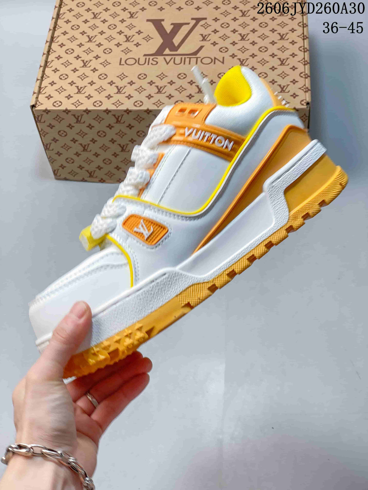 Side view of a white Trainer Maxi sneaker with orange and yellow details and a lugged outsole.