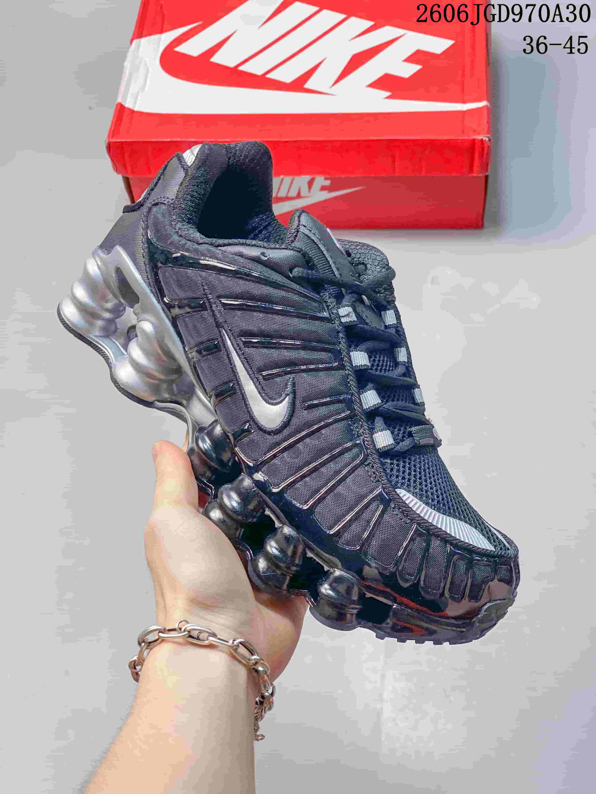 Angled side view of a dark Nike Shox TL sneaker with a silver Swoosh and sculpted sole