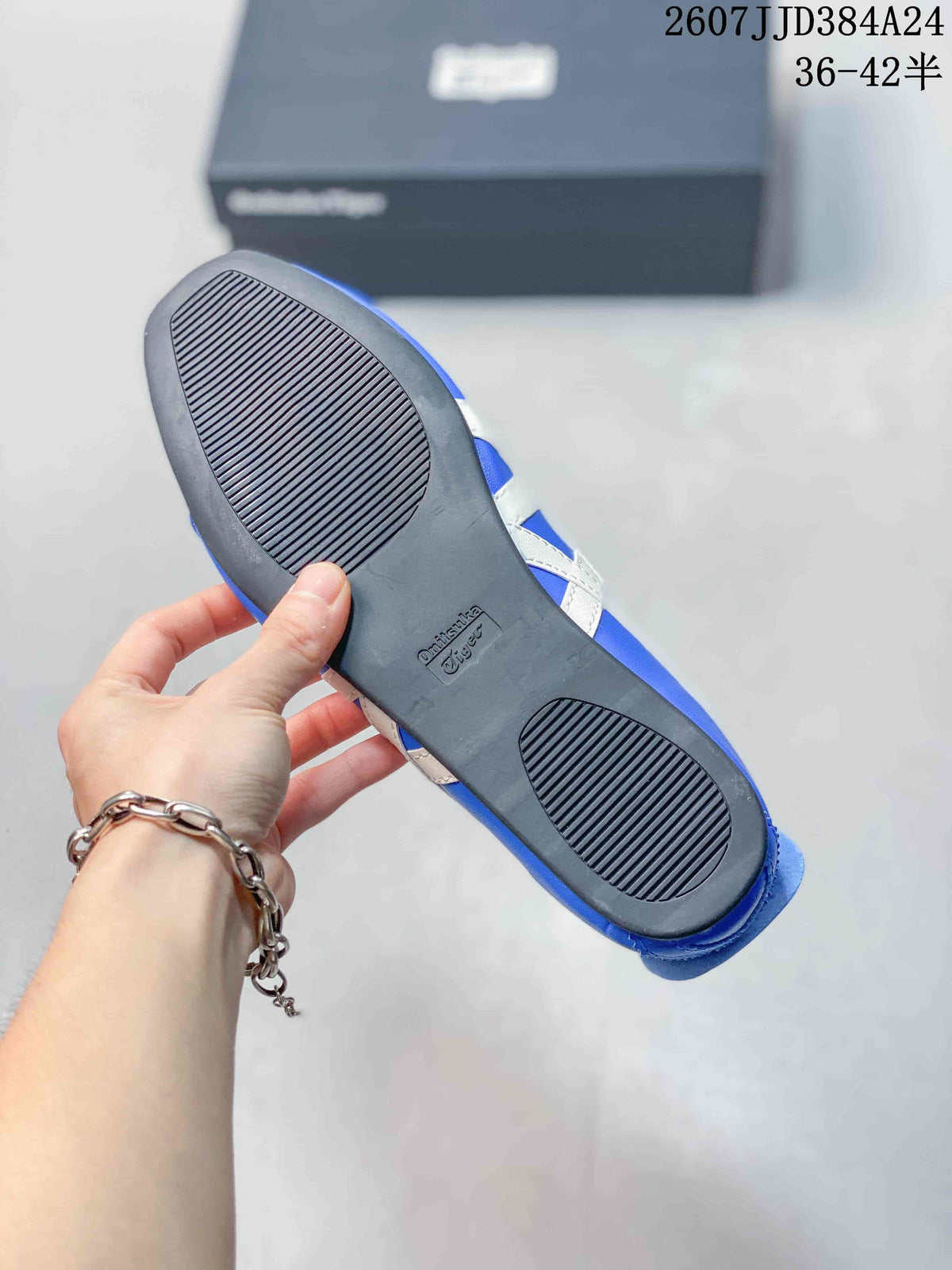 Outsole view of the blue shoe showing a black treaded sole and embossed Onitsuka Tiger branding.