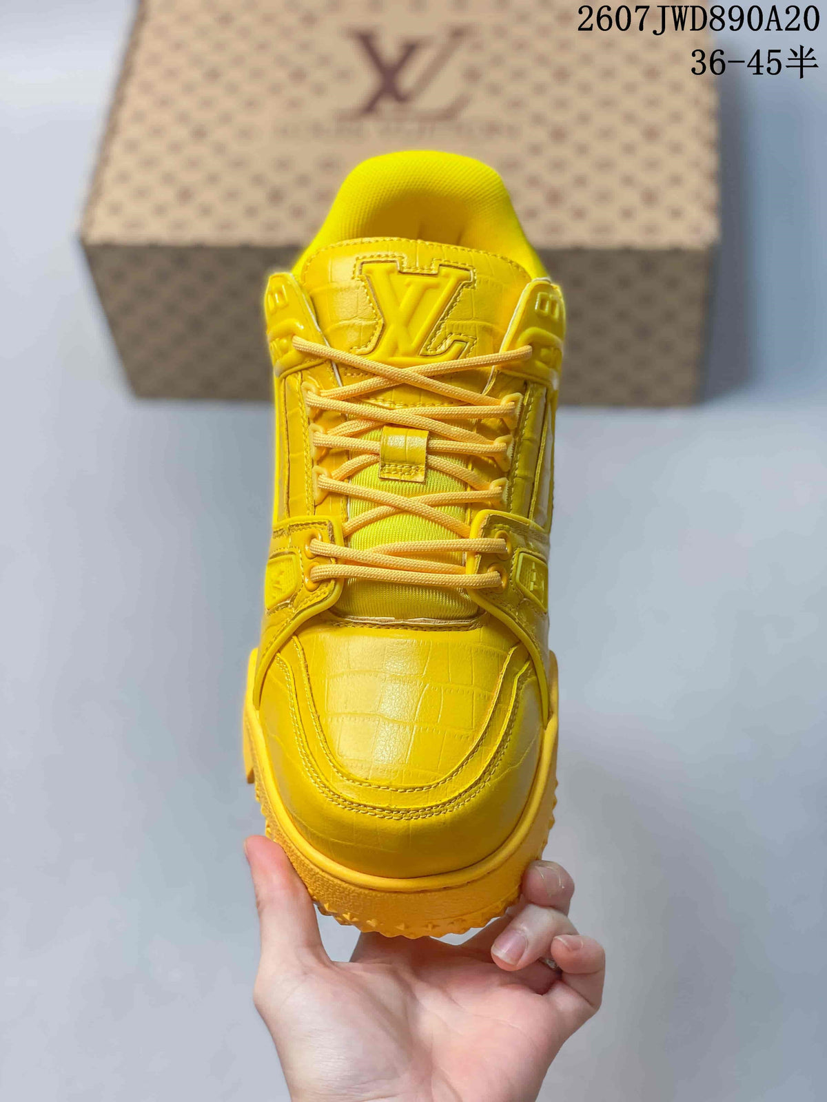 Top view of the yellow sneaker showing the rounded toe, laces, tongue and embossed monogram details.