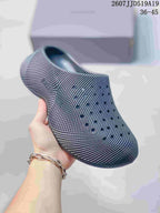 Dark gray perforated slip-on clog held in hand, showing the textured upper and open back.
