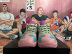 Front view of pink basketball shoes with teal and magenta patterned panels and bright green laces.