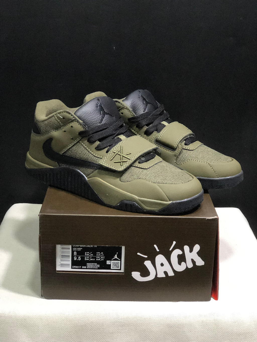 Olive and black Jumpman Jack sneakers displayed on a branded box, with the box size label visible.