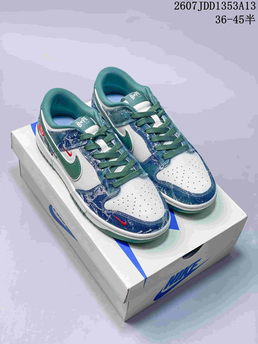 Pair of blue, white and green Nike-marked low-top sneakers displayed on a shoebox, with style code JDD1353A13 and size range 36–45 visible.
