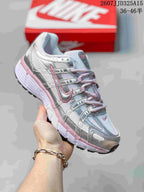 Single white and silver Nike P-6000 sneaker with pink accents held in hand, showing the layered upper, lace system and textured outsole.