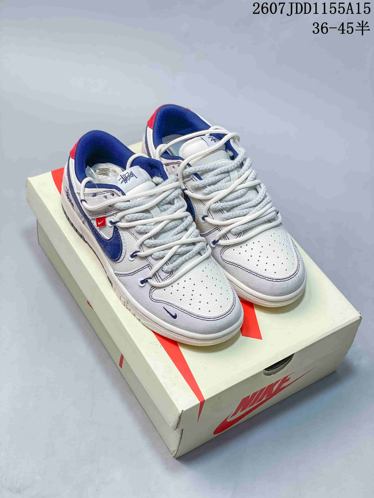 Pair of white, grey and navy Nike SB Dunk Low sneakers displayed on a Nike shoebox.