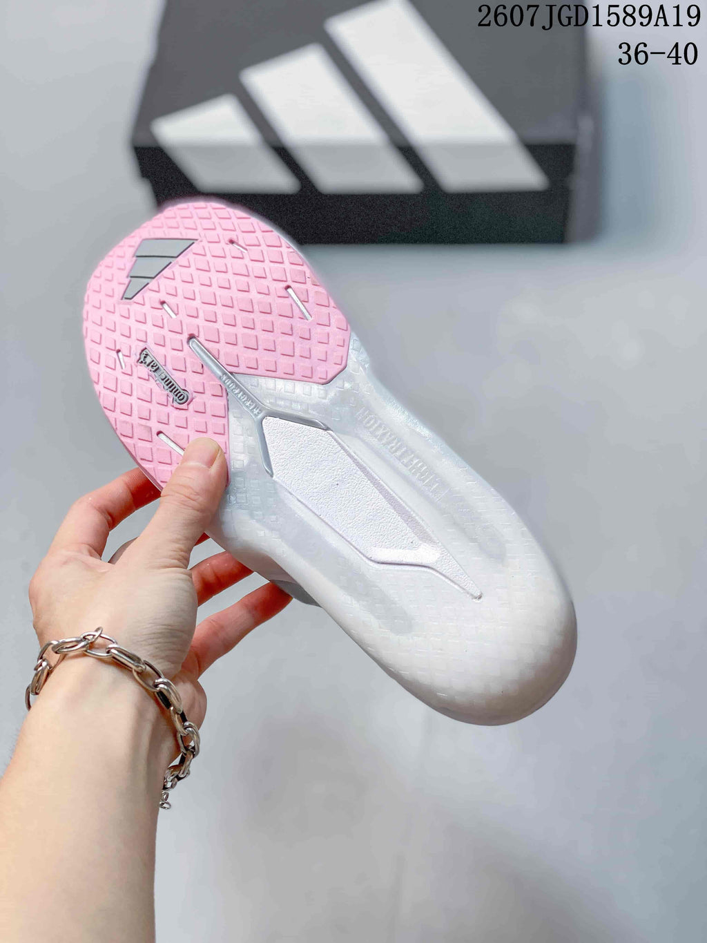 Underside view of the sneaker showing a textured white outsole with pink tread sections and gray structural details.