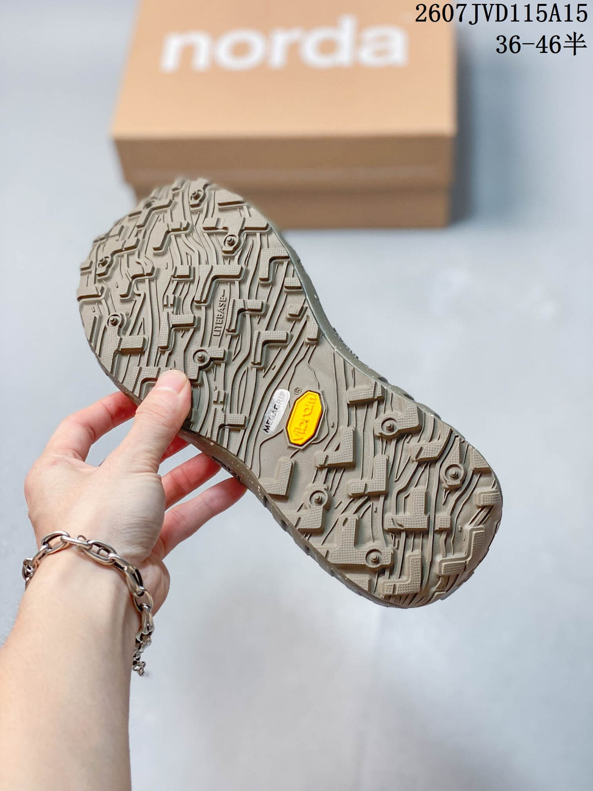 Close-up of the patterned sneaker outsole showing visible Vibram and Megagrip markings, with the branded box in the background.